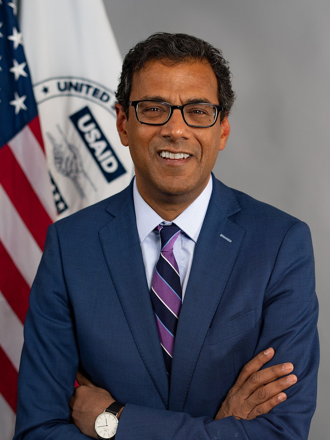 Official portrait of Atul Gawande in a suit, arms folded.
