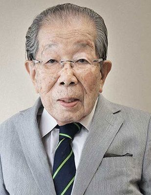 Shigeaki Hinohara in a grey suit and striped tie.